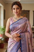 Woman wearing a pink saree with a blue border indoors.