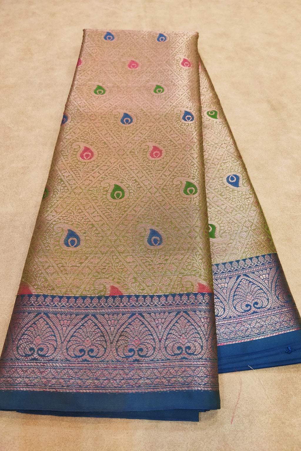 Beige saree with blue border and colorful patterns on a beige background