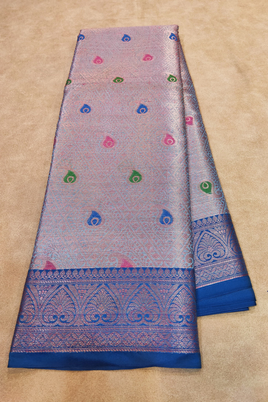 Saree with blue border and colorful patterns on a beige background