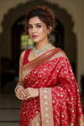 Woman wearing a red saree with gold patterns in an indoor setting