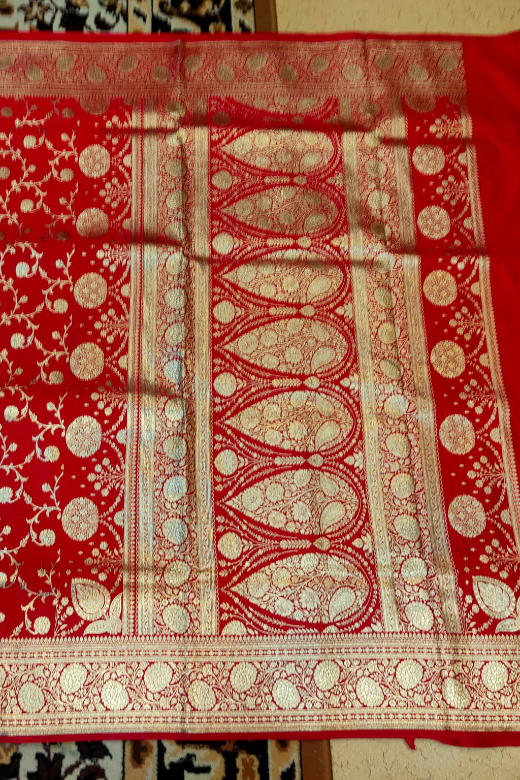 Red fabric with gold patterns on a textured surface