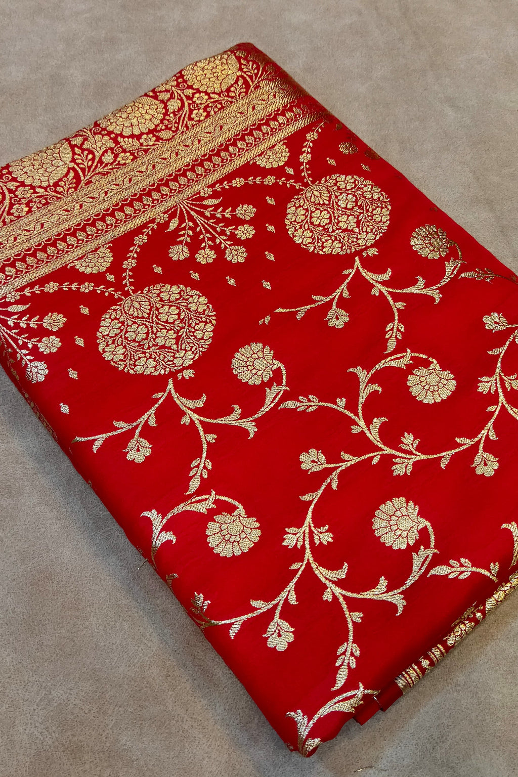 Red fabric with gold floral patterns on a beige surface