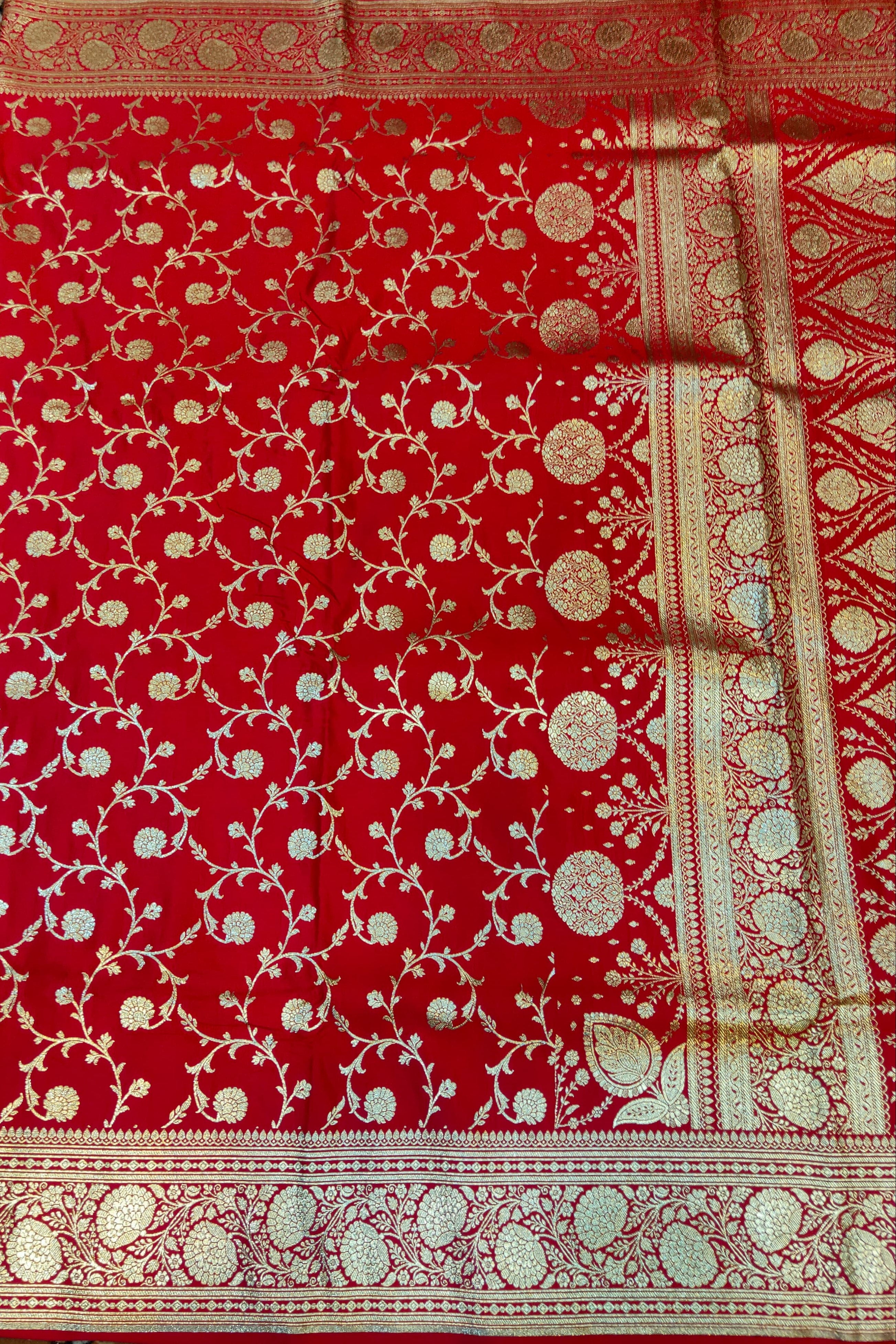 Red fabric with gold and white patterns on a textured surface