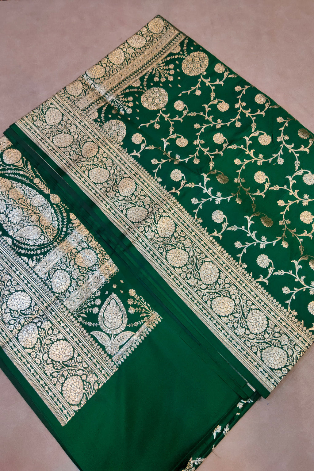 Green saree with gold and white floral patterns on a pink background