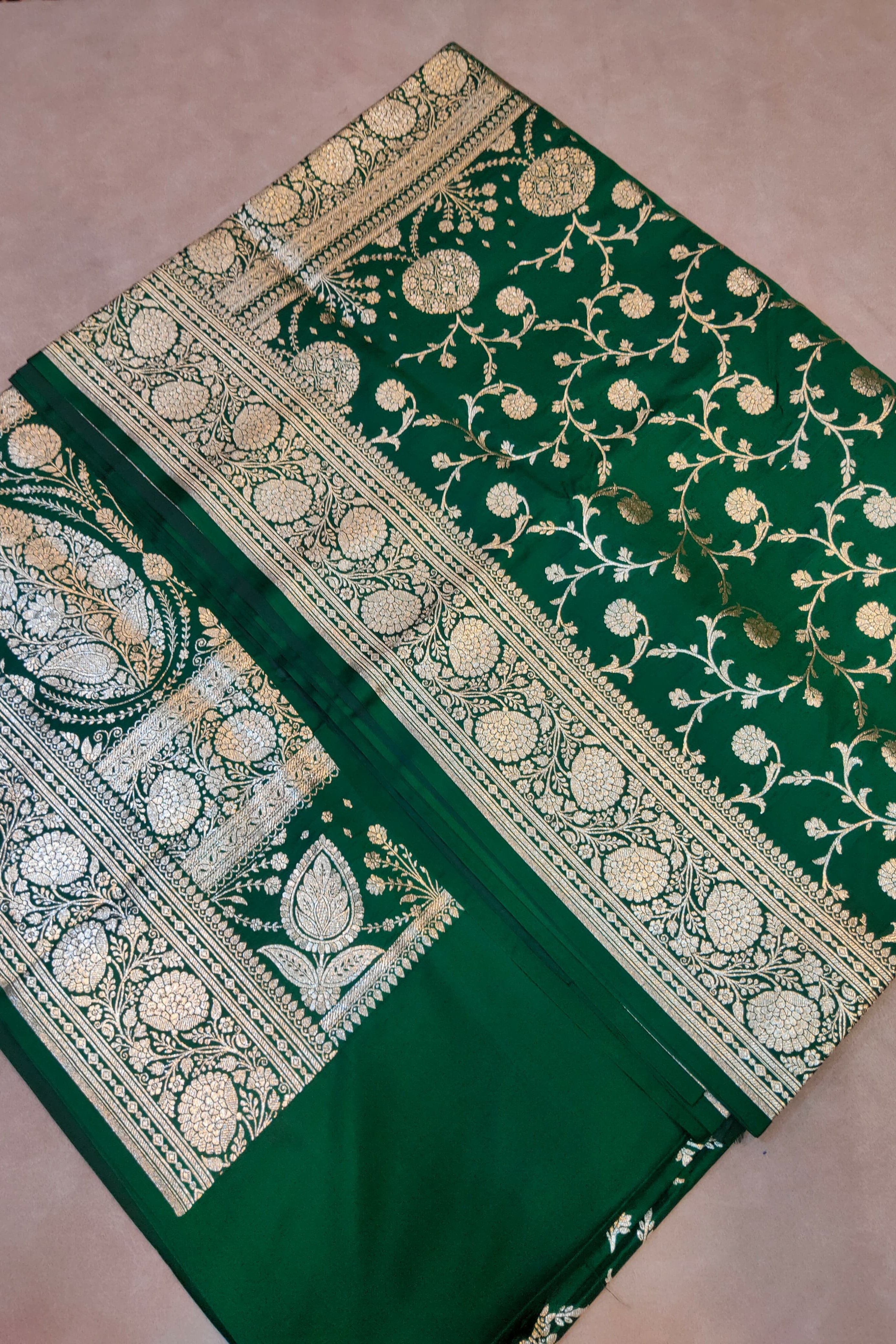 Green saree with gold and white floral patterns on a pink background