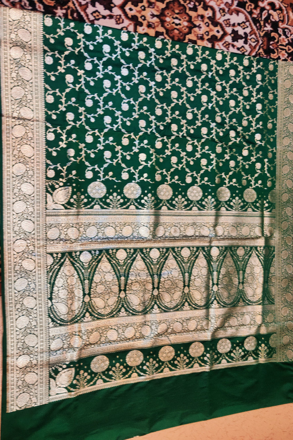 Green fabric with intricate white patterns on a brown background
