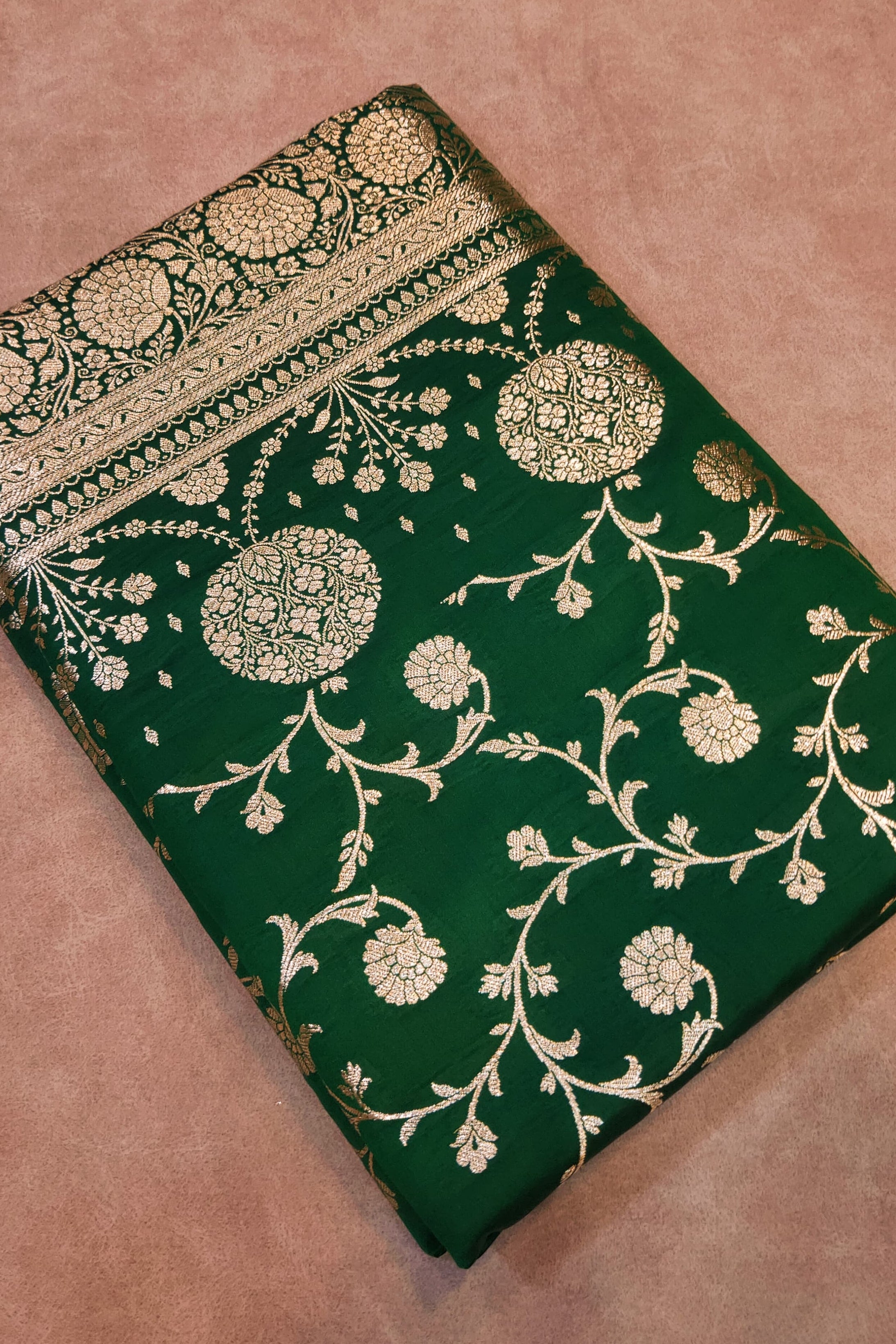 Green fabric with gold embroidery on a brown background