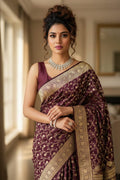 Woman in a traditional maroon saree with gold patterns indoors