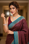 Woman wearing a maroon saree with blue border indoors