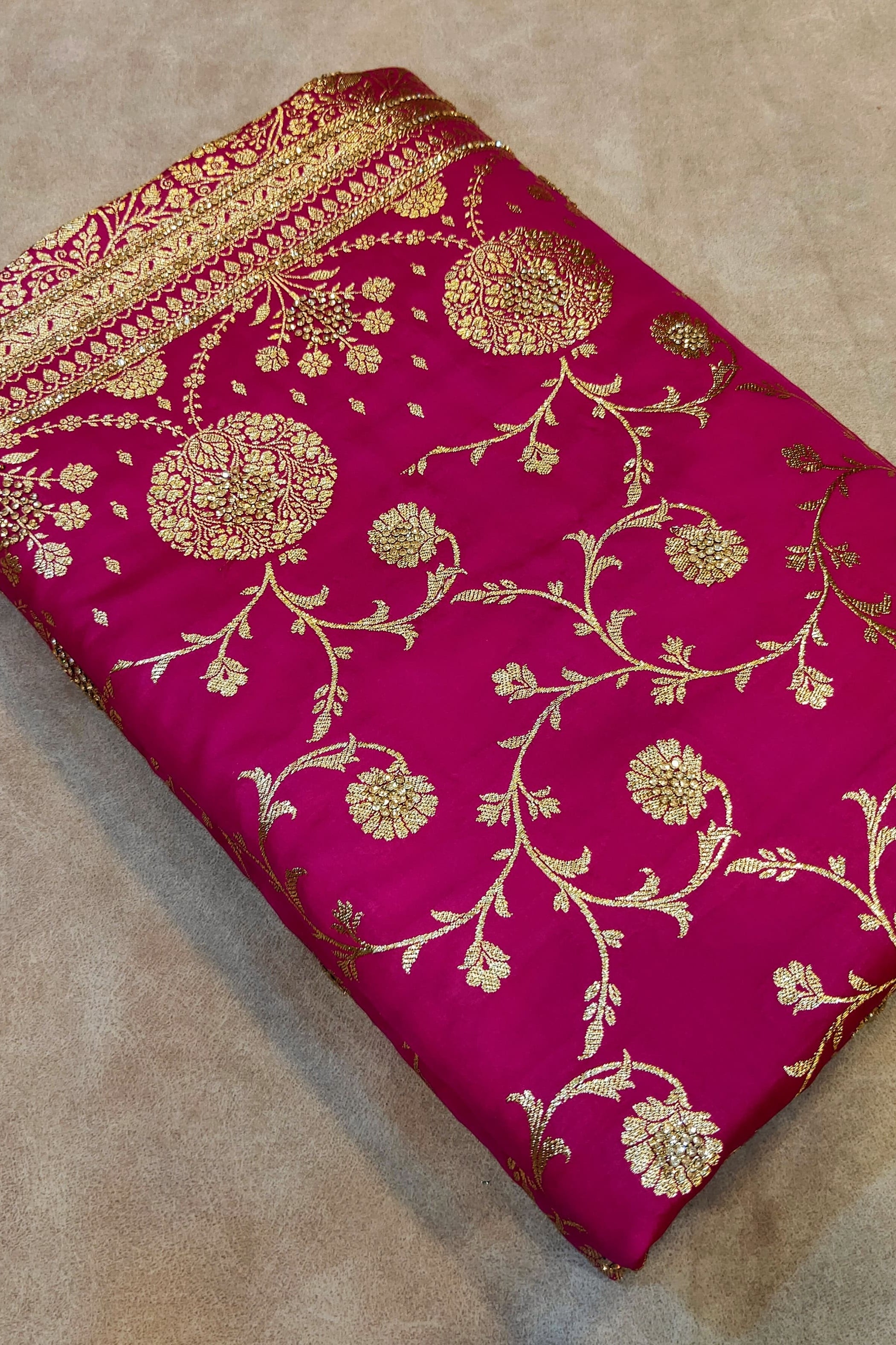 Pink fabric with gold embroidery on a beige surface