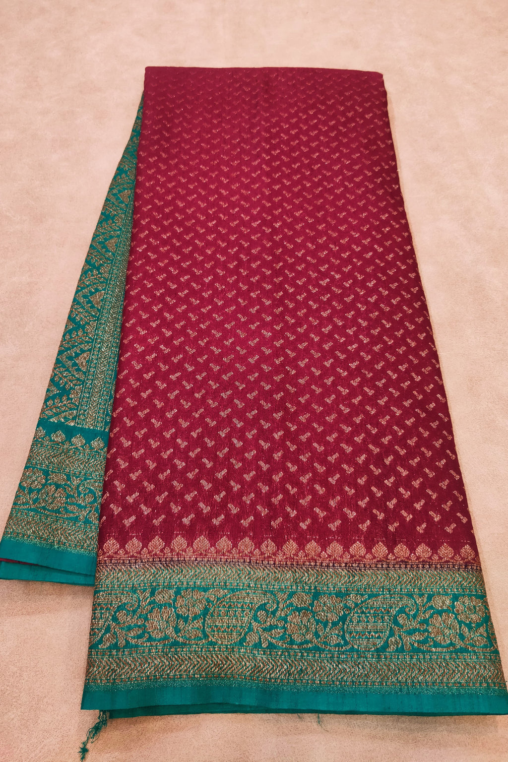 Maroon fabric with green border on a beige background