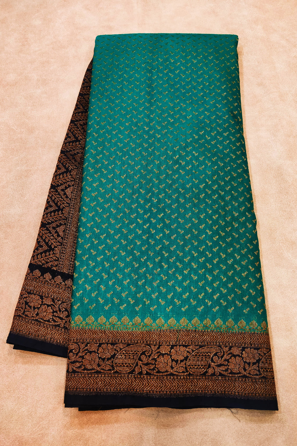 Teal fabric with black border on a beige background