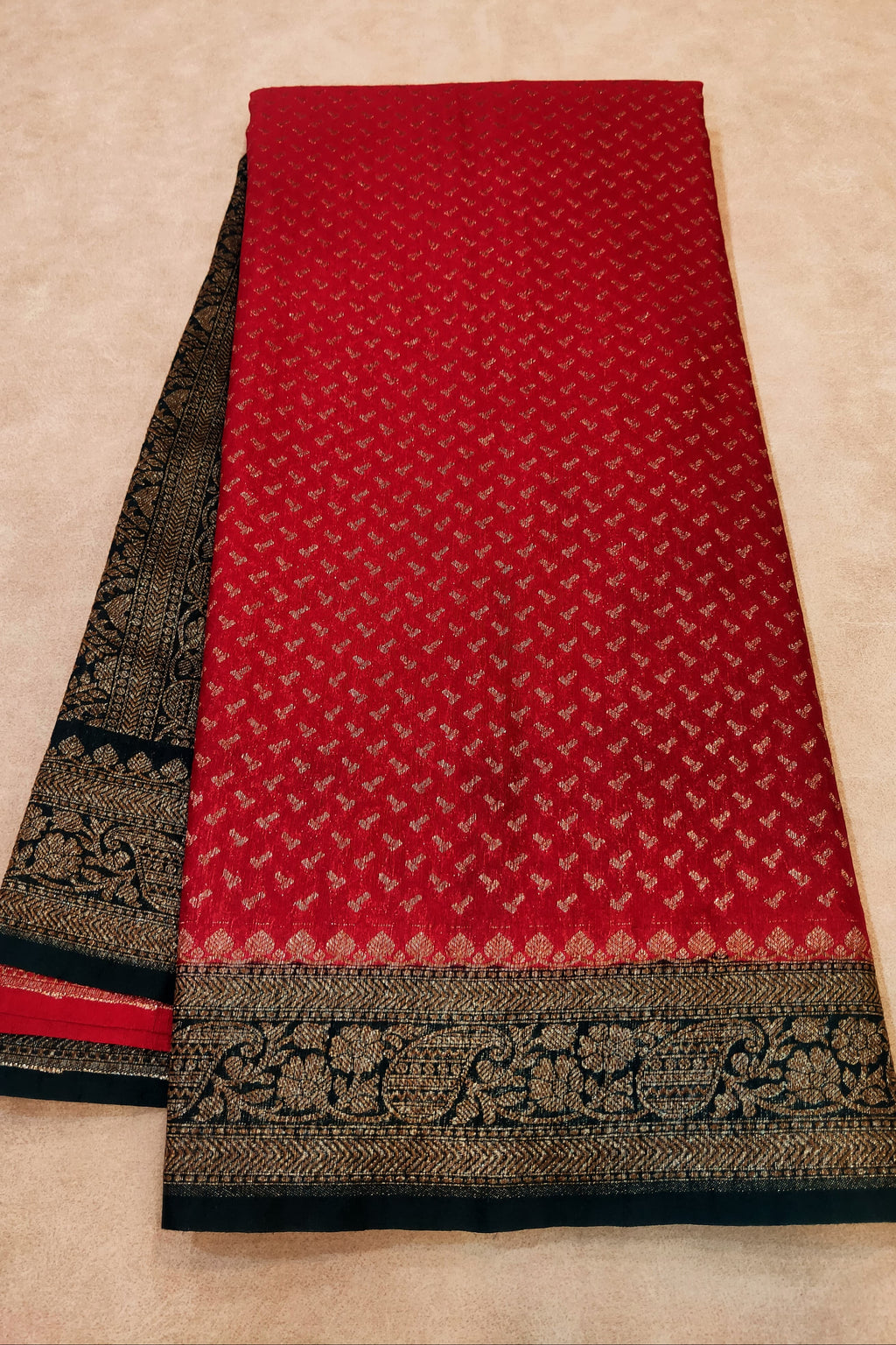 Red fabric with black and gold border on a beige background