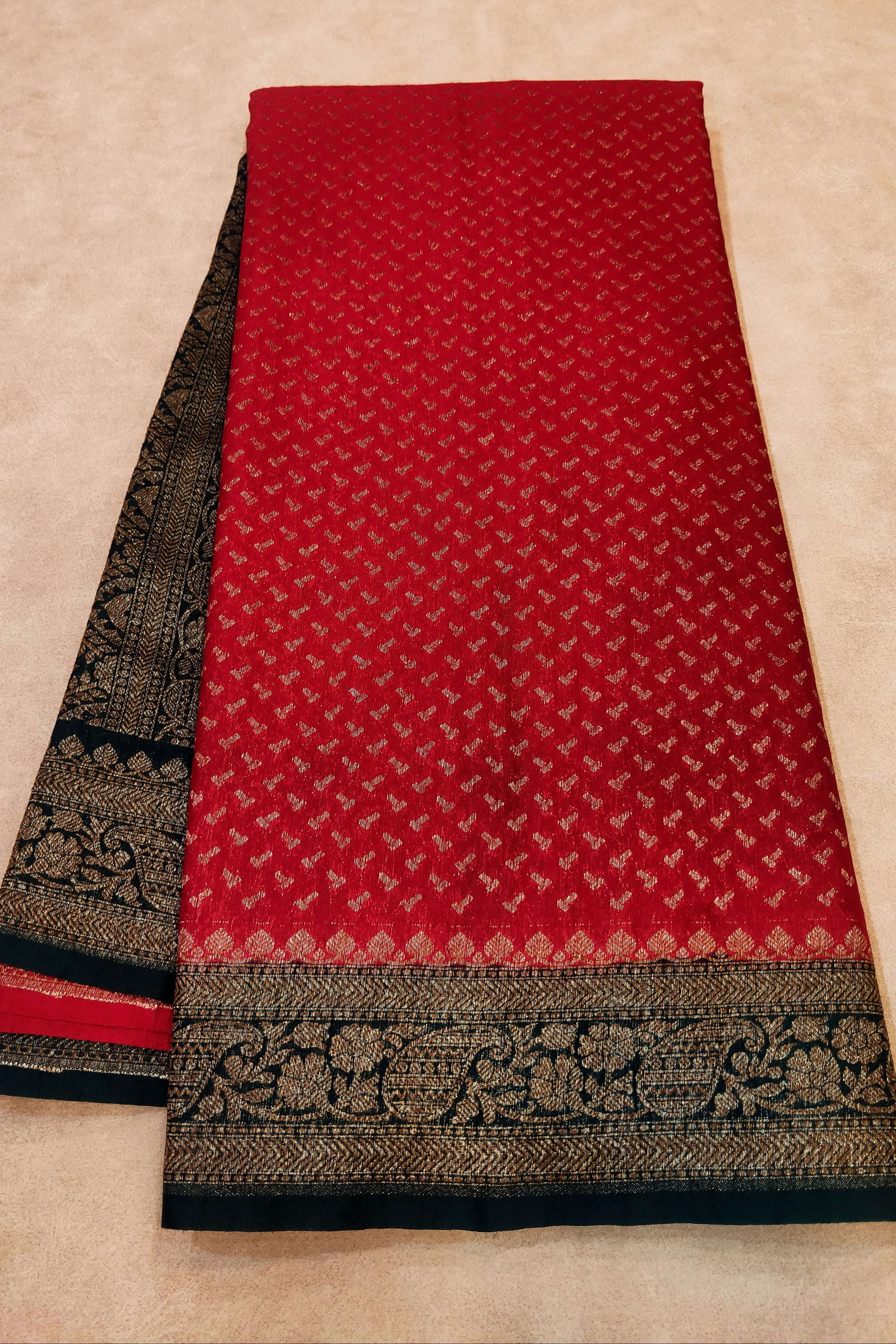 Red fabric with black and gold border on a beige background