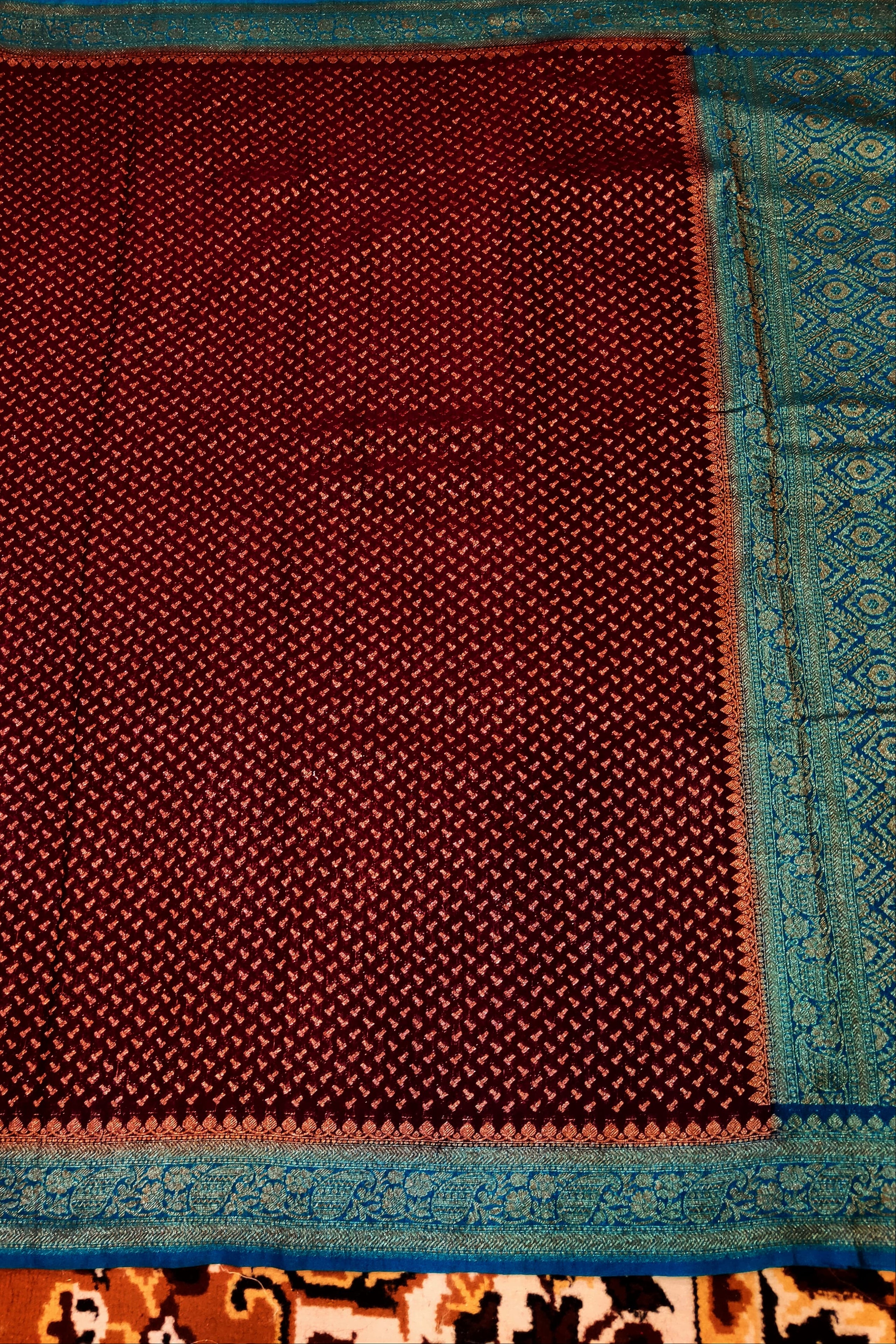 Maroon fabric with blue border on a patterned background