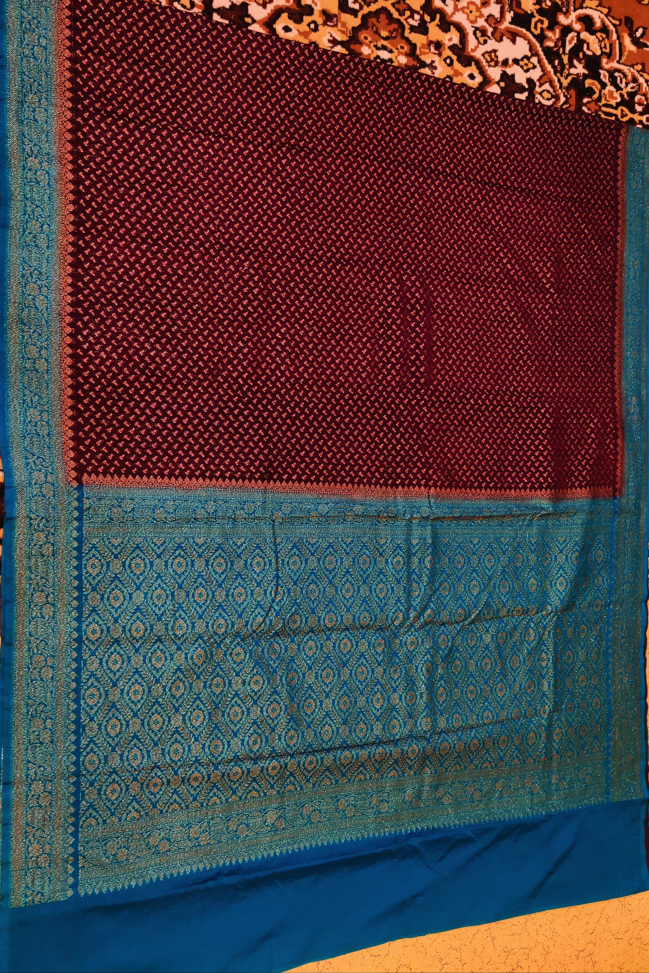 Maroon and blue fabric with intricate patterns on a textured background