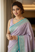Woman wearing a lavender saree with a blue border indoors