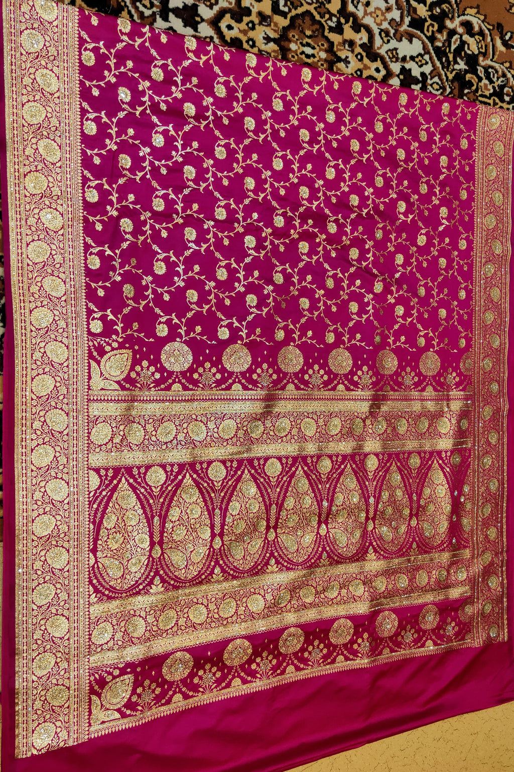 Pink saree with gold patterns on a textured background