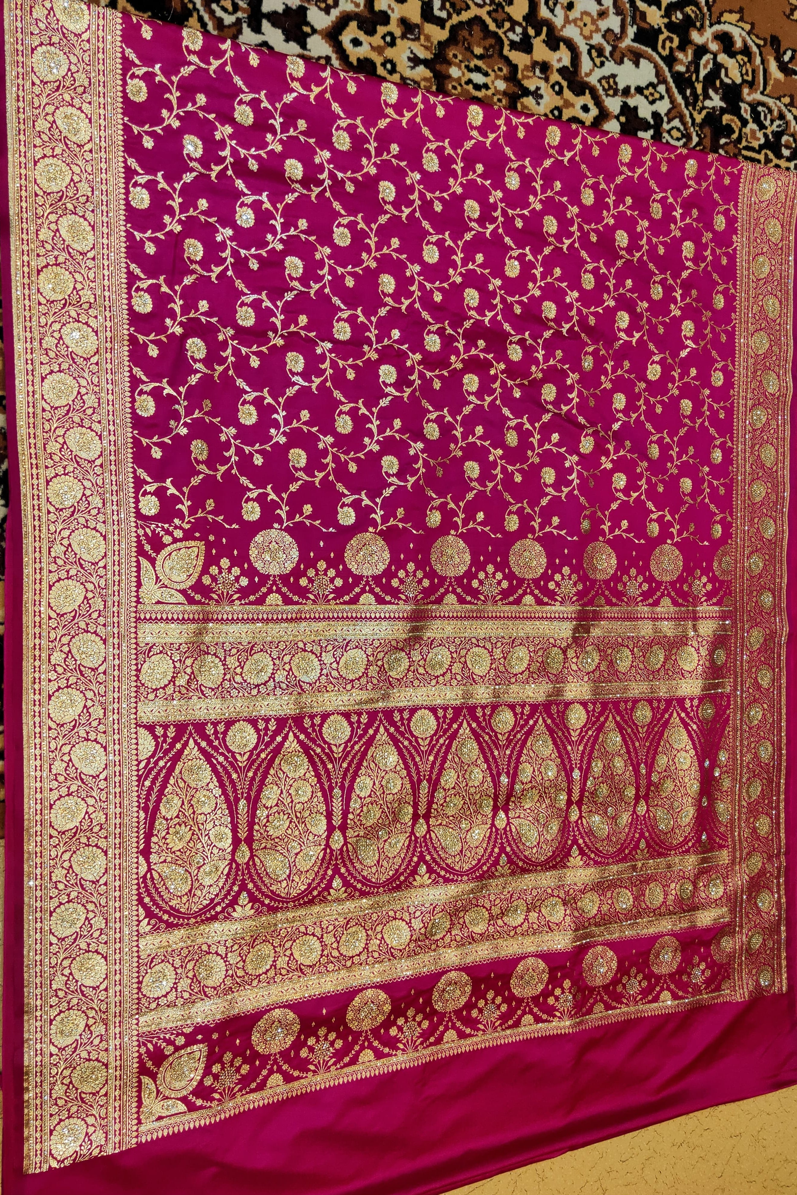 Pink saree with gold patterns on a textured background