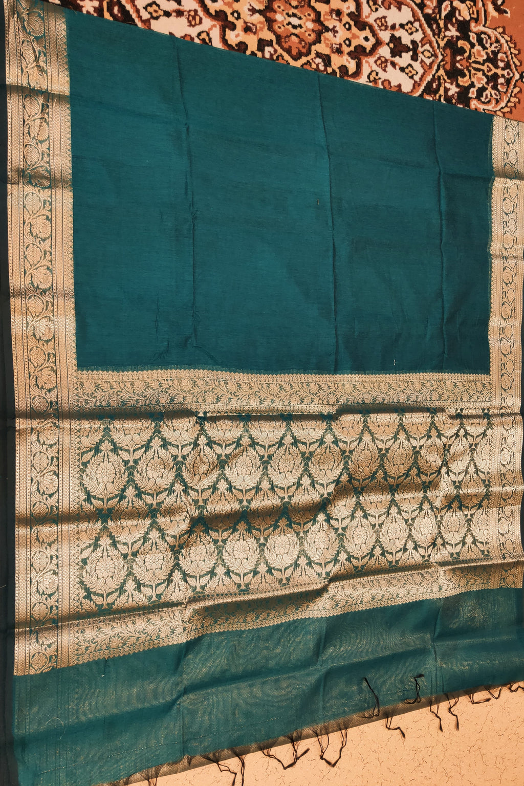 Teal fabric with intricate white patterns on a decorative background