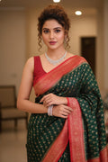 Woman wearing a green and red saree with jewelry indoors.