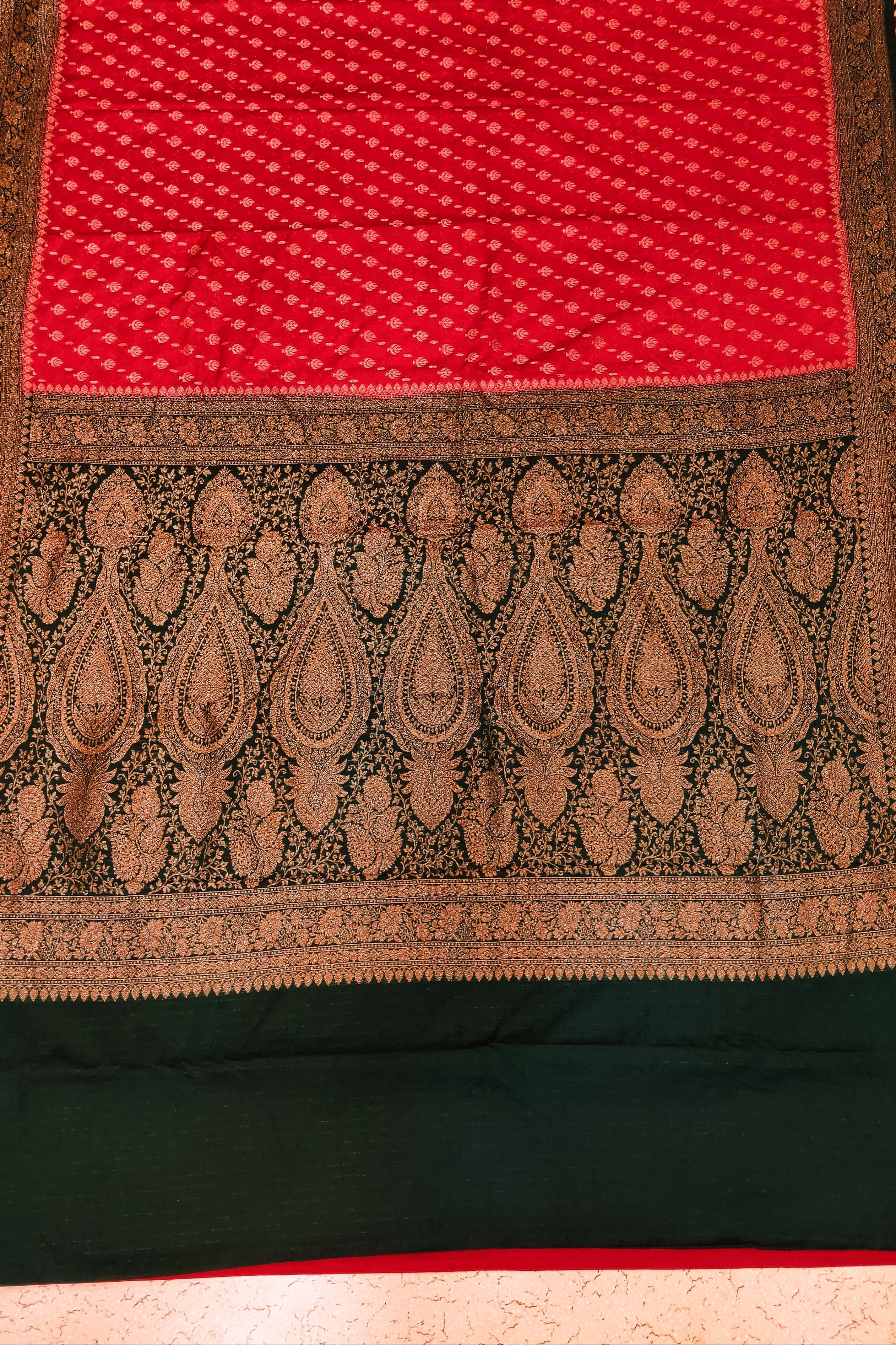 Traditional saree with red and green patterns on a patterned background
