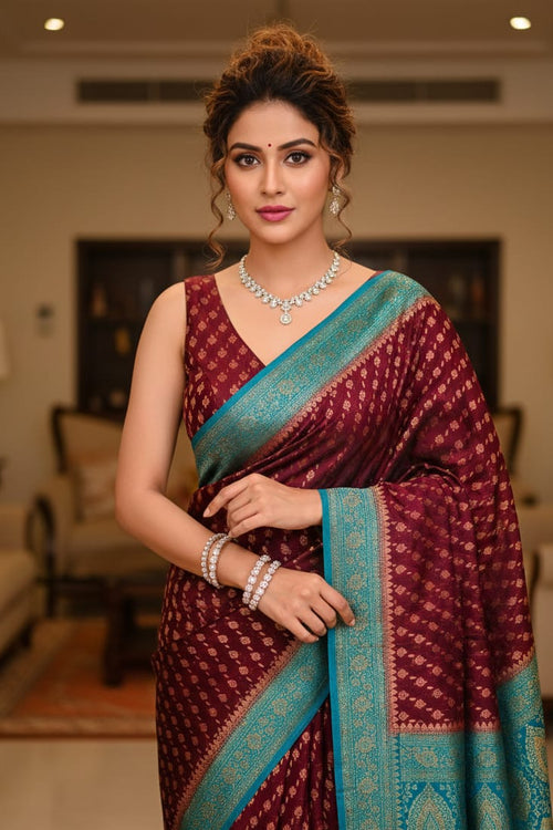 Woman in a maroon and blue saree with jewelry in an indoor setting
