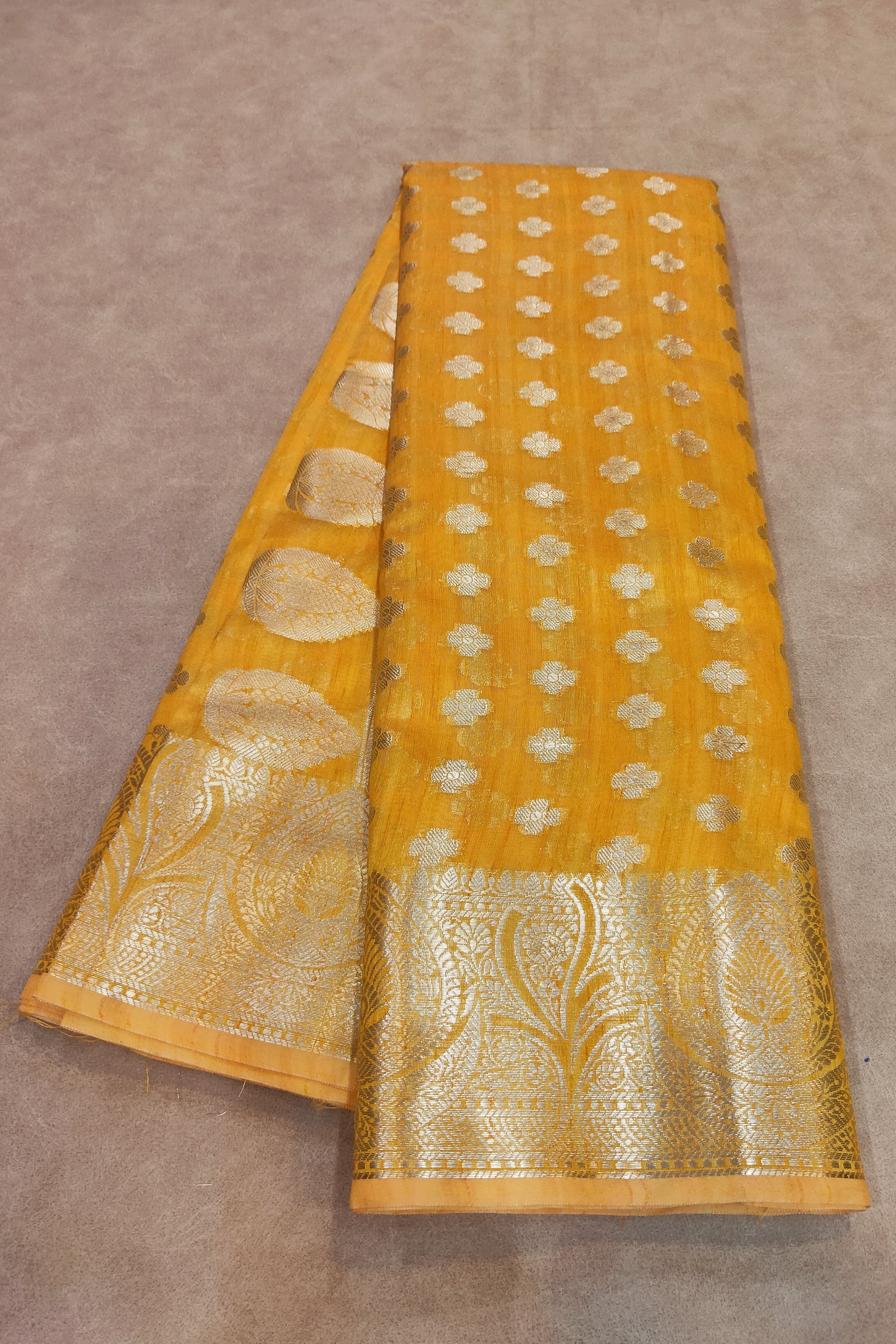 Yellow fabric with gold patterns on a brown background