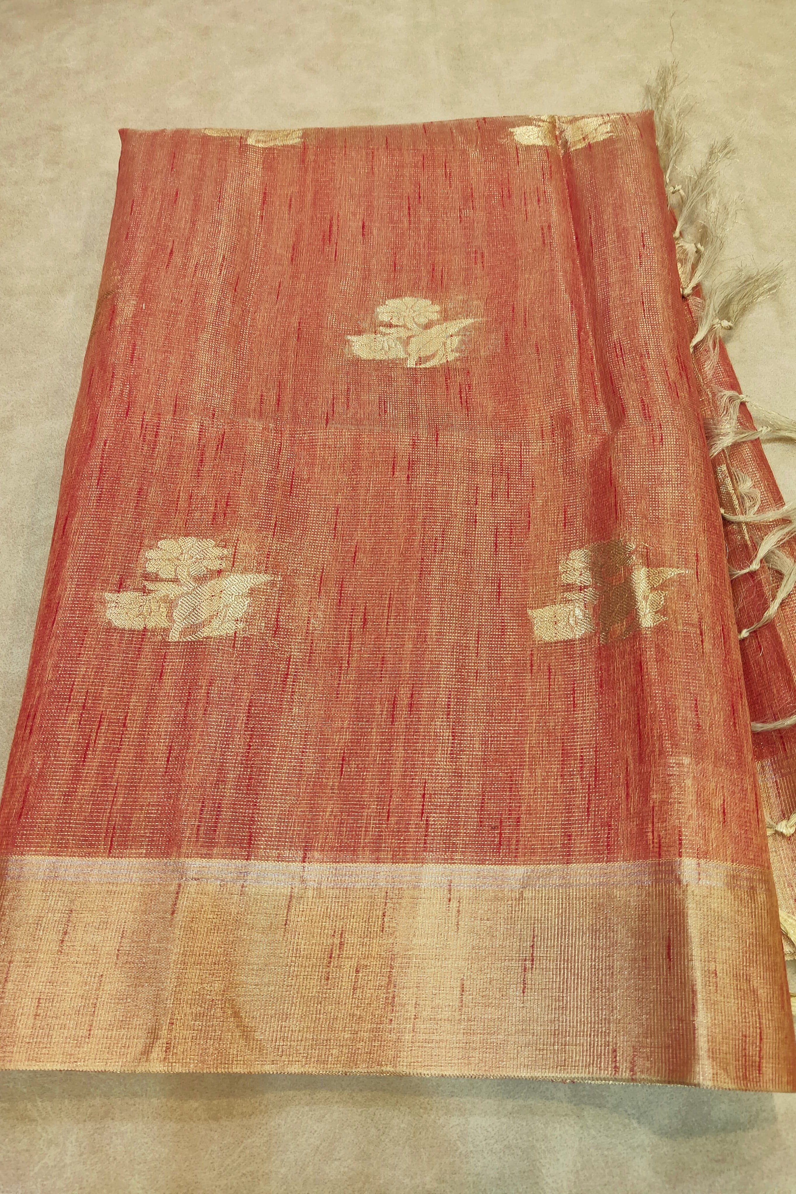 Red fabric with gold patterns and tassels on a beige background