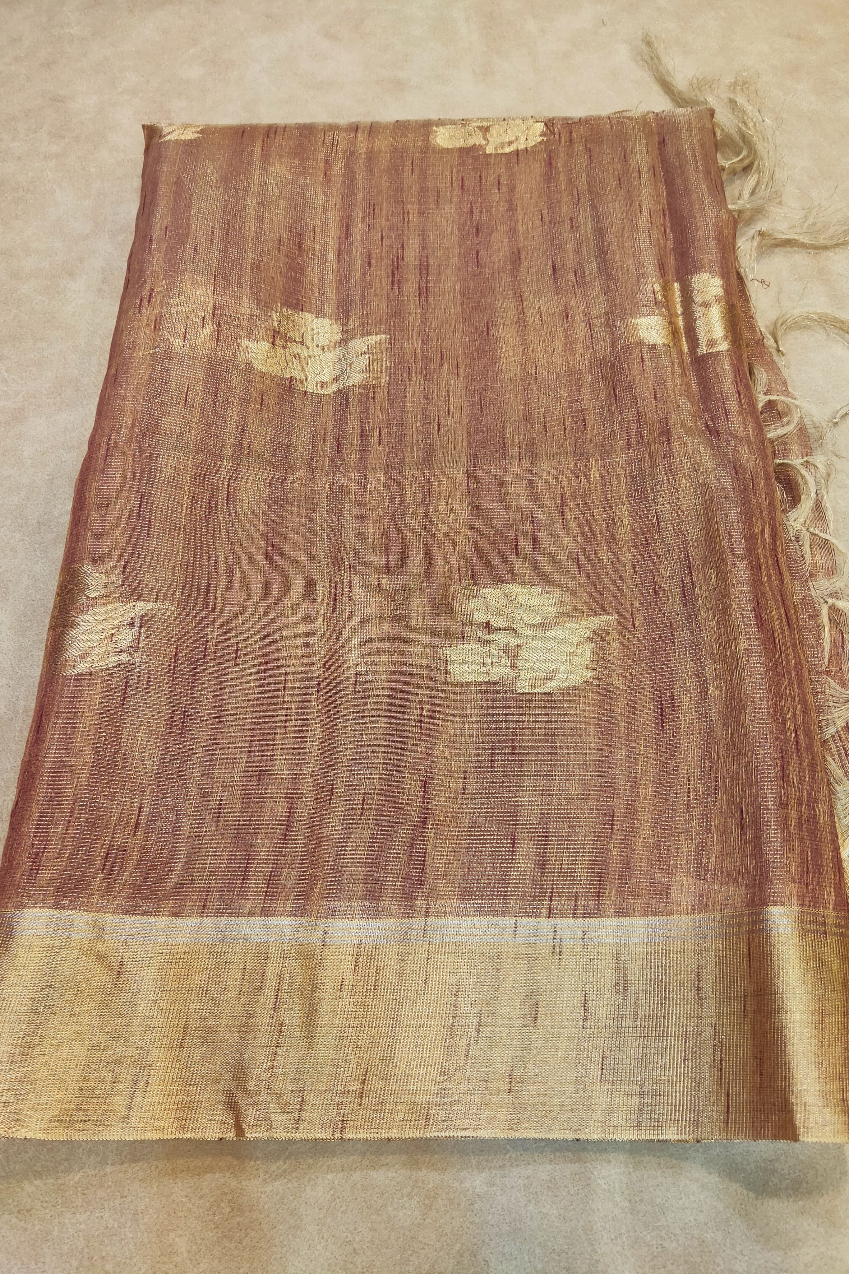 Brown fabric with gold patterns and trim on a beige background