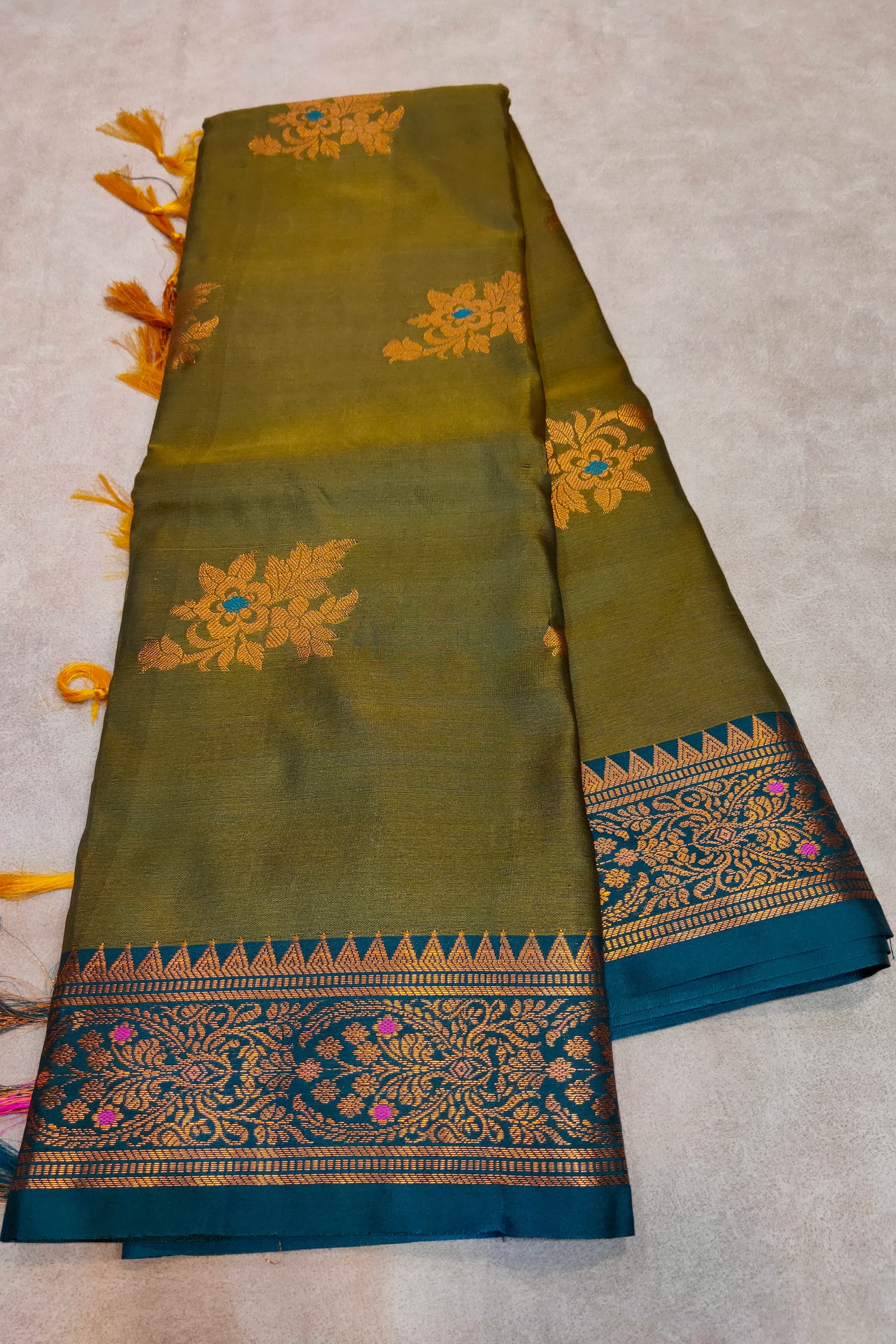 Green saree with gold and blue embroidery on a light gray background